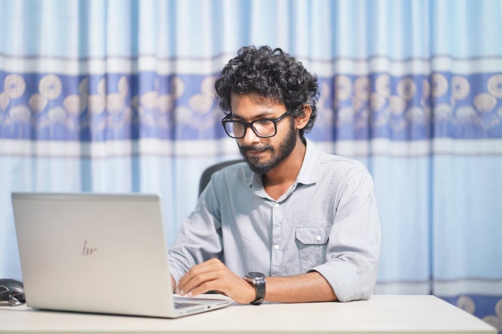 A focused young man using a laptop in a well-lit room. Ideal for themes of productivity and tech.